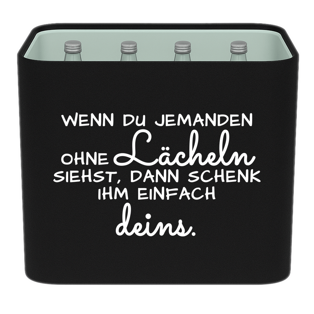 Schwarze KistenBlende mit weißem Spruch „Wenn du jemanden ohne Lächeln siehst, dann schenk ihm einfach deins.“ – Wasser Glas.