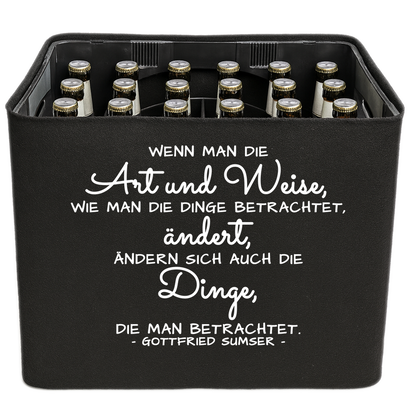 Schwarze KistenBlende mit weißem Spruch „Wenn man die Art und Weise, wie man die Dinge betrachtet, ändert, ändern sich auch die Dinge, die man betrachtet. — Gottfried Sumser“ – Bier 24 × 0,33 l und Bier 20 × 0,5 l.