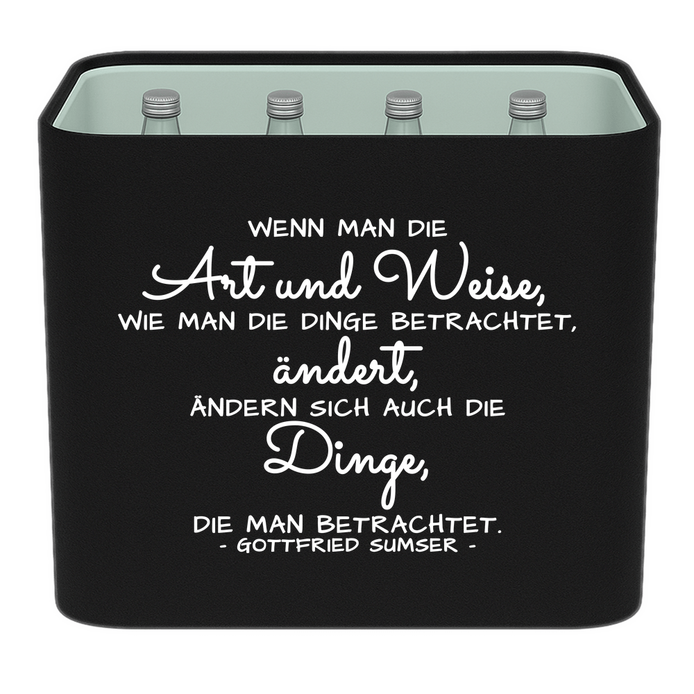 Schwarze KistenBlende mit weißem Spruch „Wenn man die Art und Weise, wie man die Dinge betrachtet, ändert, ändern sich auch die Dinge, die man betrachtet. — Gottfried Sumser“ – Wasser Glas.